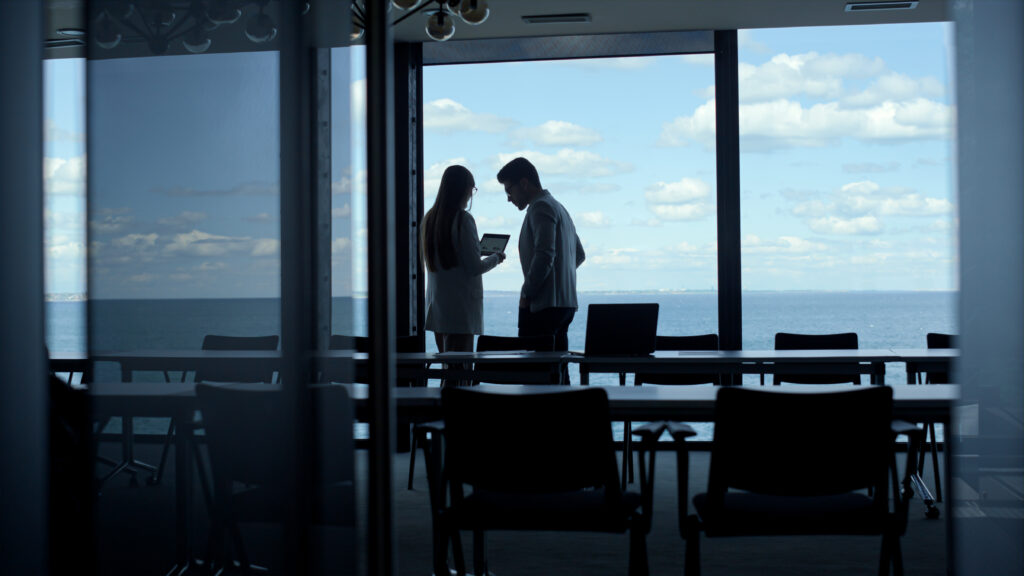 Silhouette business people using tablet in marine view office. Partners talking